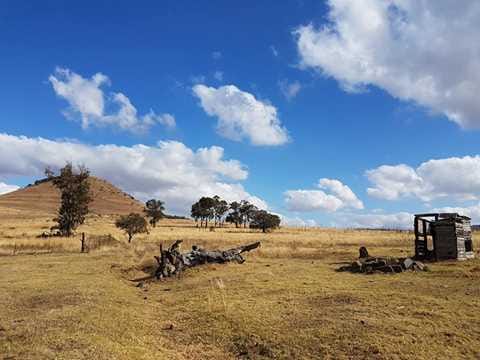 Vast African landscape with a hill, clouds, and a small wooden structure, representing Renegade Relief Services' field operations