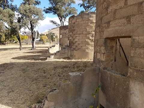 Ruins of brick structures in a dry, grassy area, likely a project site.