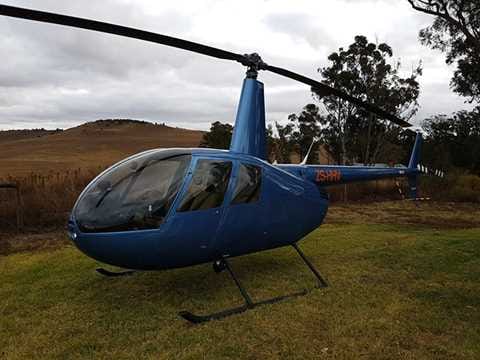 Blue helicopter parked on grass in a field, used for relief services.